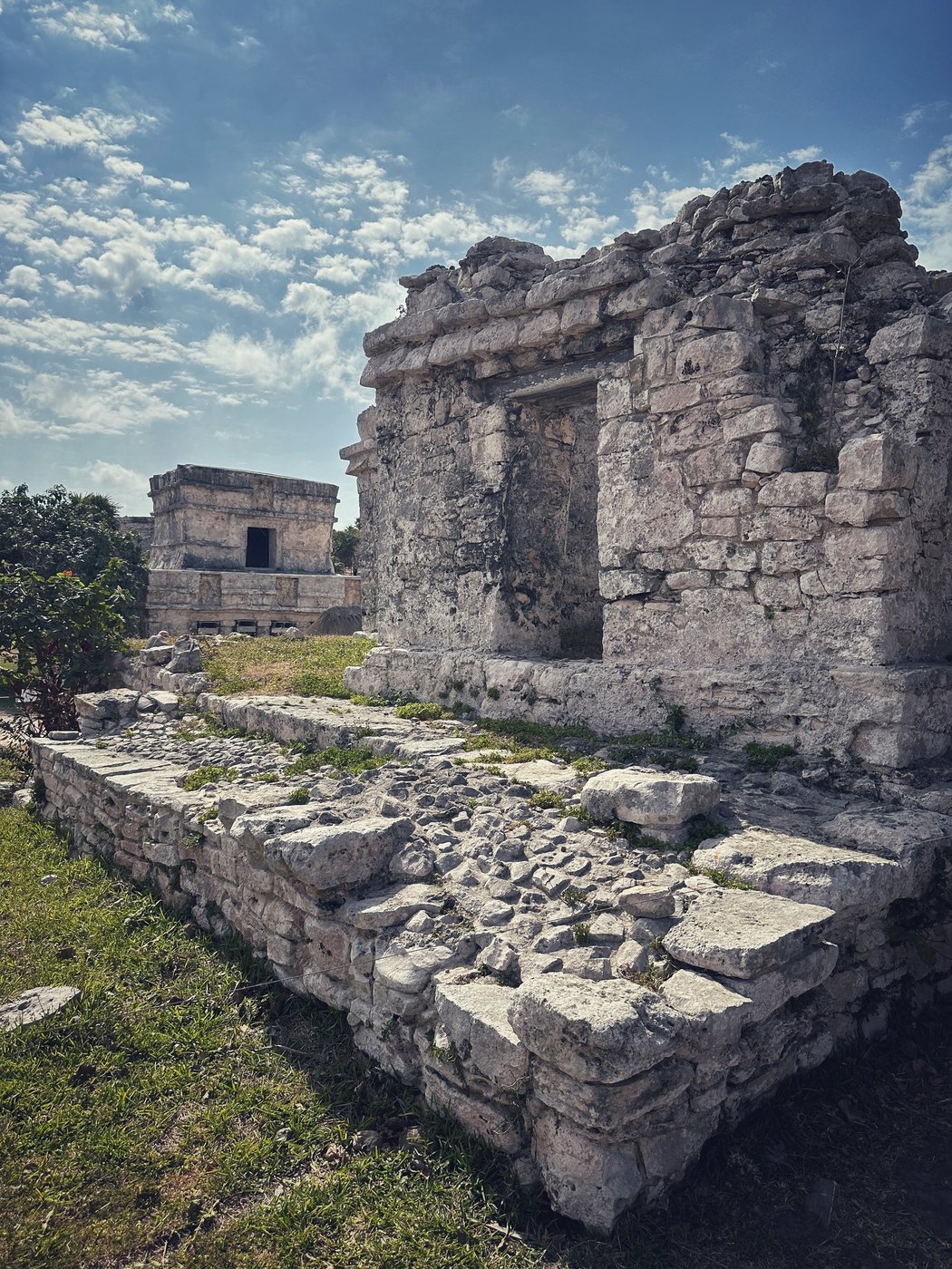 Crumbling stone ruins with a dark doorway beside a low rubble wall on green grass