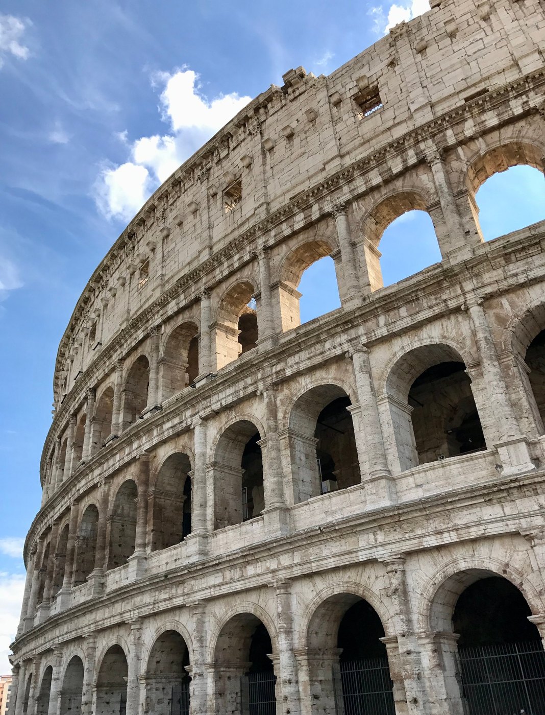 Tiered stone arches of an ancient amphitheater curving against a blue sky